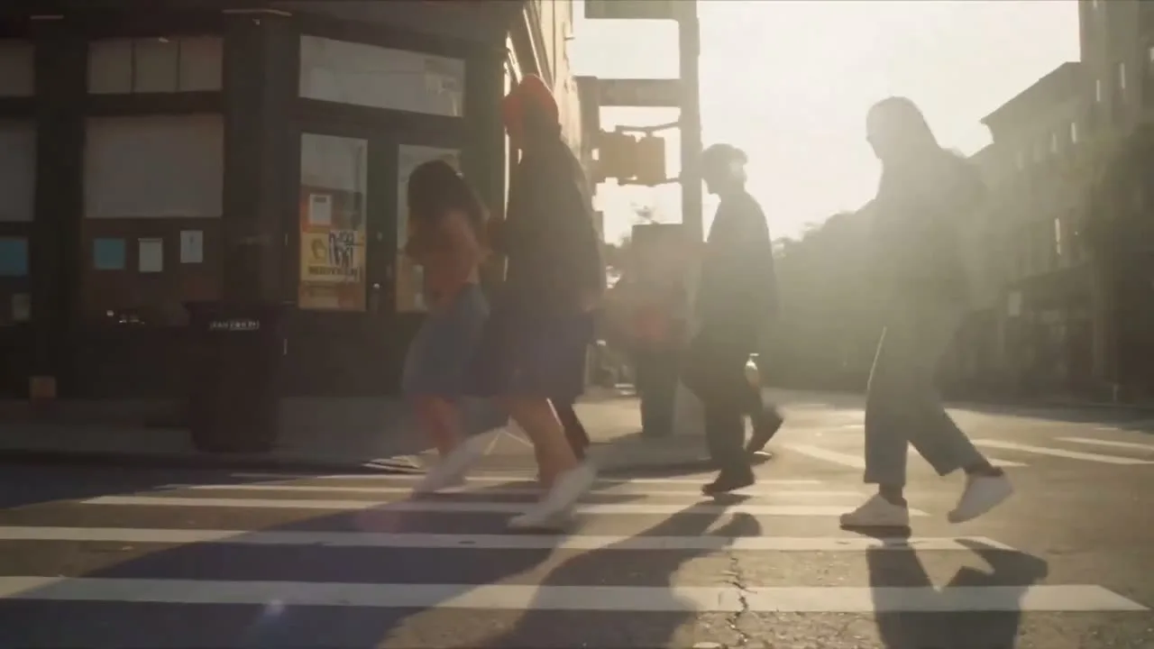 Before: pedestrians crossing in low sun, the woman in the red cap wearing a long dark coat
